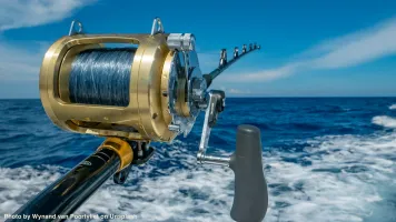 Sports fishing rod and reel in a boat's wake.
