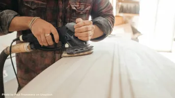 A surfboarder shaper working on a new surfboard