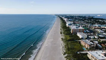 A stunning aerial view of Cocoa Beach with sandy beaches and urban waterfront buildings.