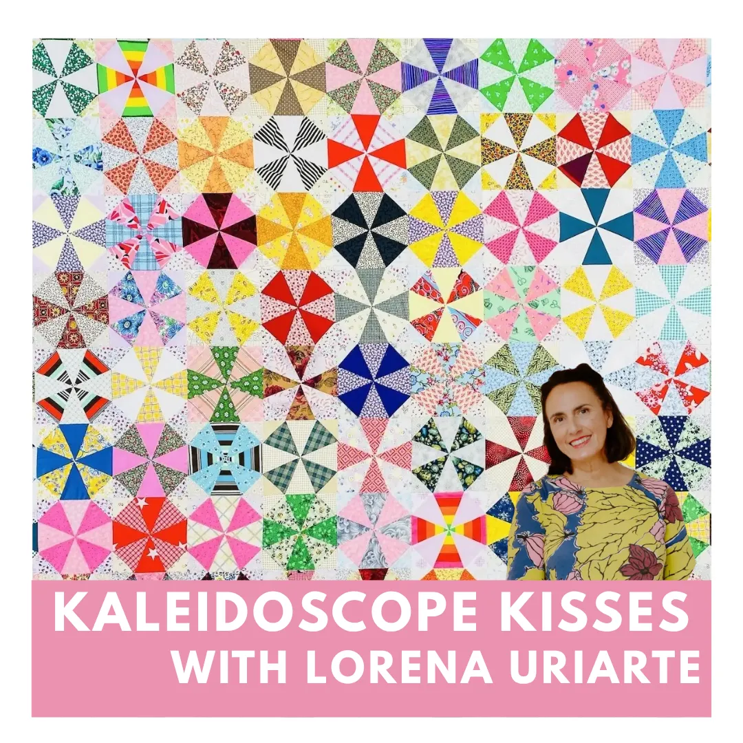 Colorful whimsical quilt with triangular circus tents, toys, and geometric shapes on a pink background bordered with colorful triangles and diamonds. No human shapes or faces.