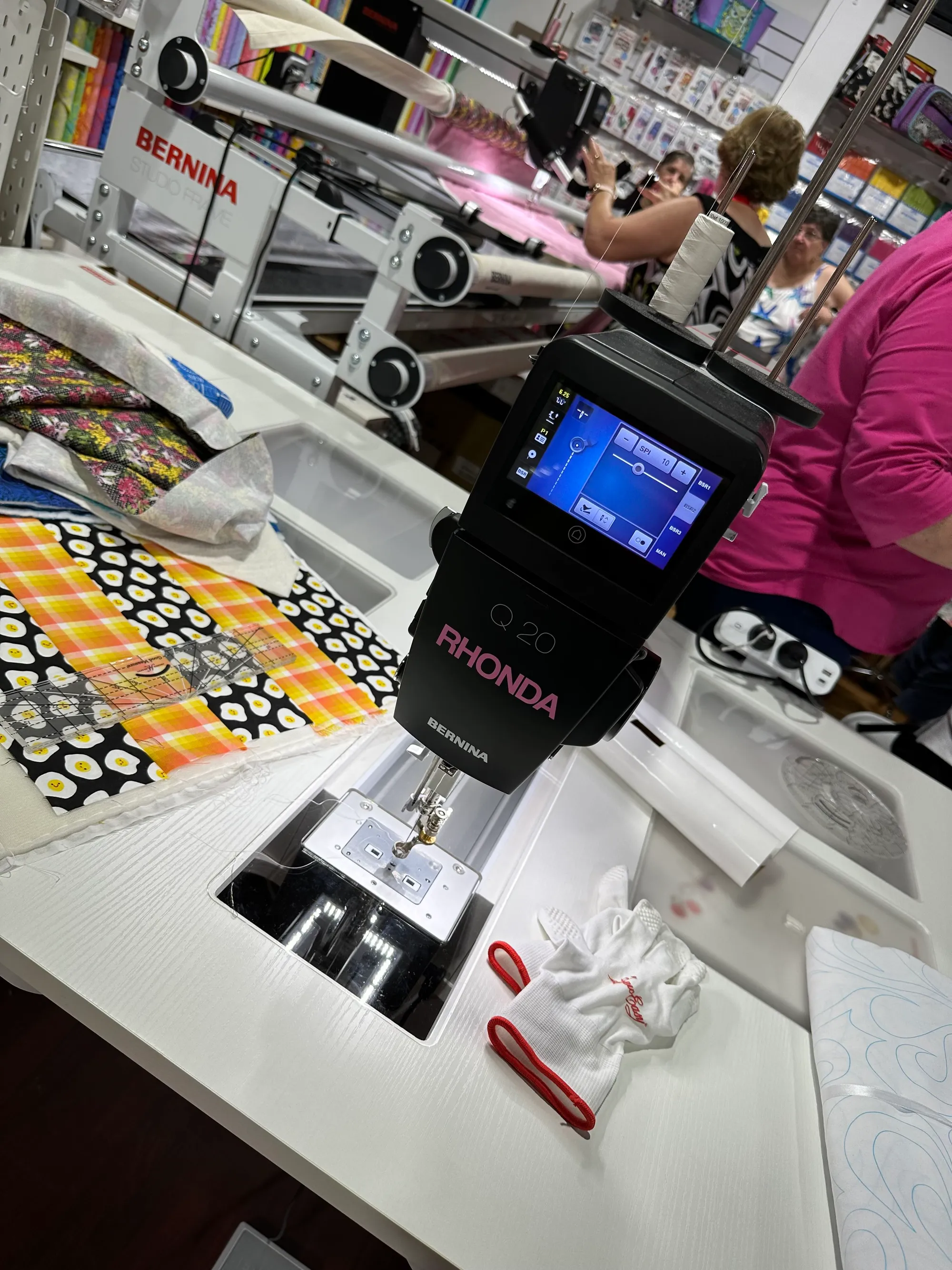 Colorful whimsical quilt with triangular circus tents, toys, and geometric shapes on a pink background bordered with colorful triangles and diamonds. No human shapes or faces.