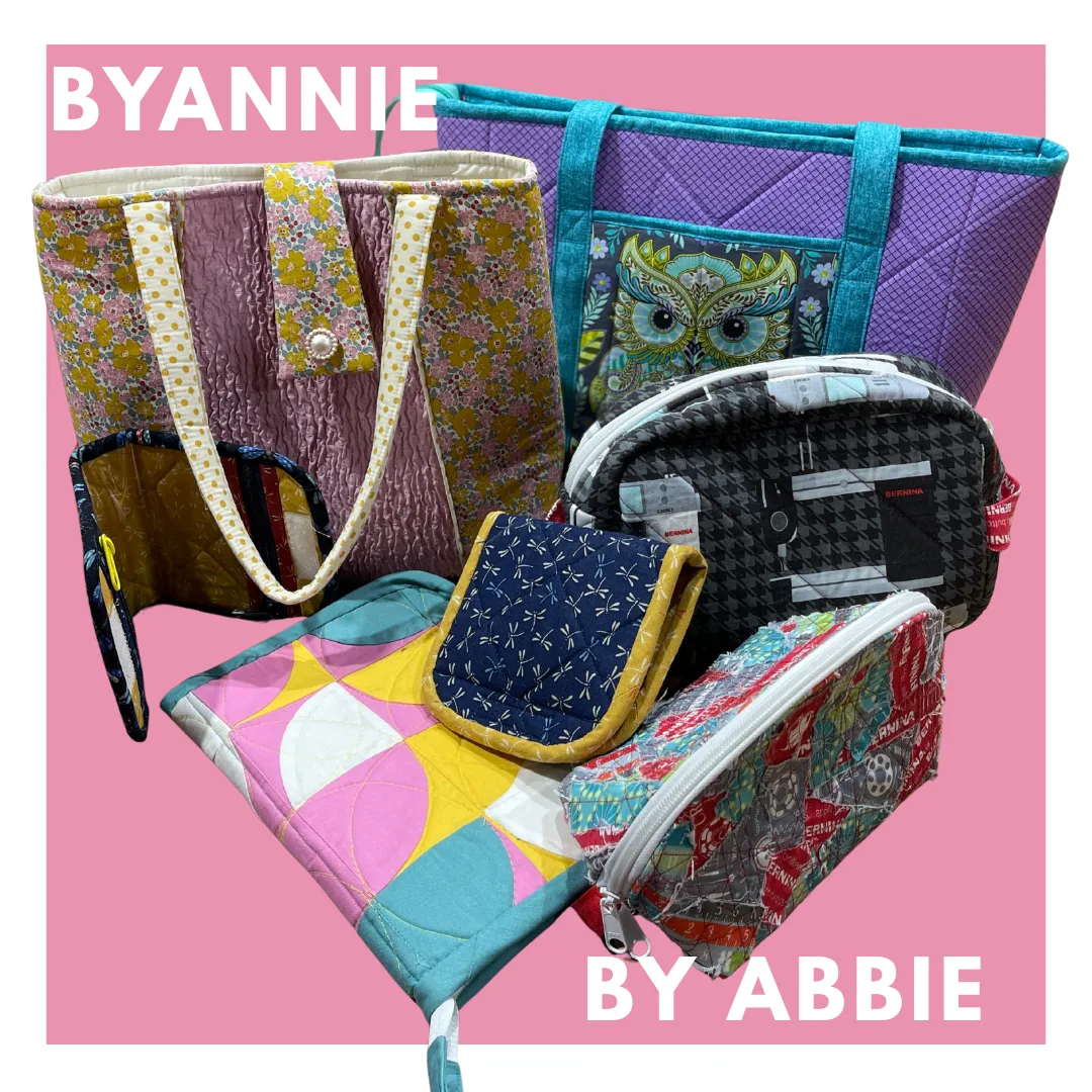 Colorful whimsical quilt with triangular circus tents, toys, and geometric shapes on a pink background bordered with colorful triangles and diamonds. No human shapes or faces.