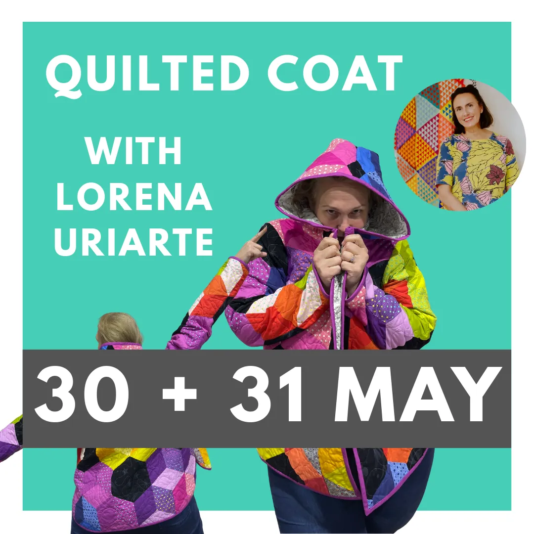 Colorful whimsical quilt with triangular circus tents, toys, and geometric shapes on a pink background bordered with colorful triangles and diamonds. No human shapes or faces.