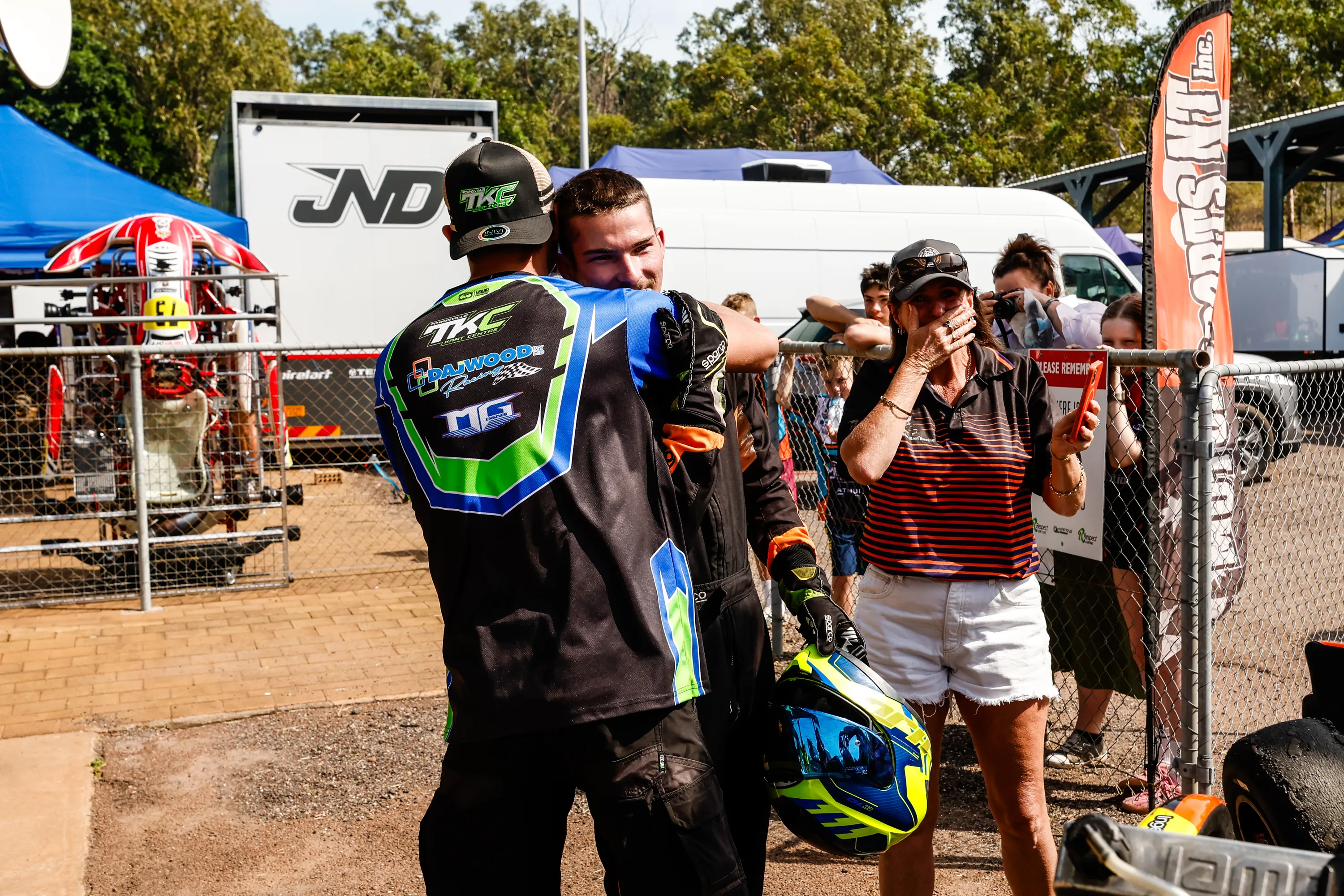 TKC race-day mentor — support under the tent. Shows a professional kart racing pit environment with technical support and mentoring. No human shapes.